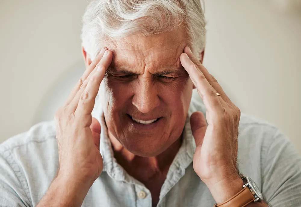 Senior man, hands on head with headache pain and painful stress migraine. Elderly people are at risk for arthritis, cancer and heart disease as well as mental health issues like anxiety or depression